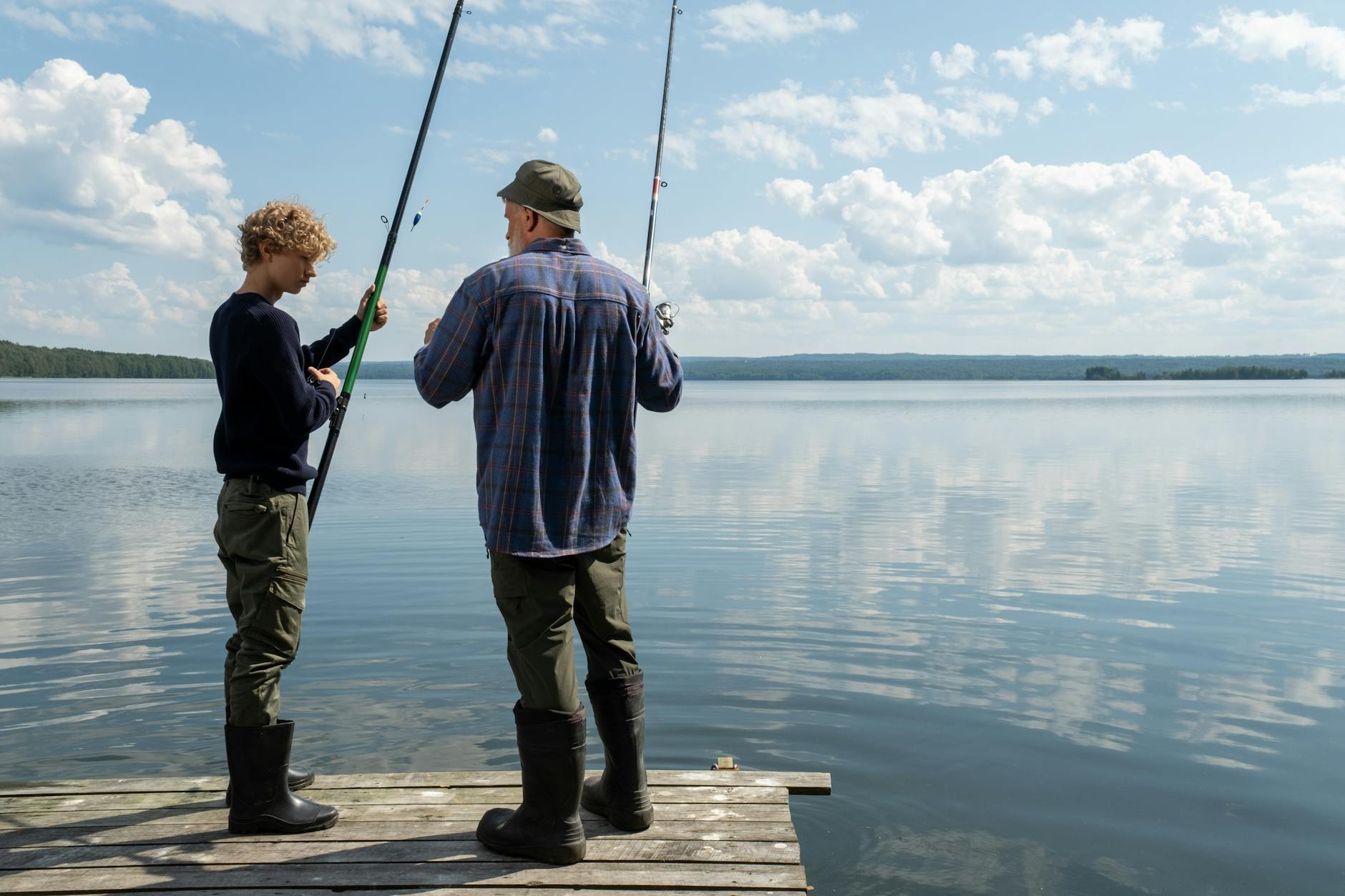father and son standing on a pier and fishing